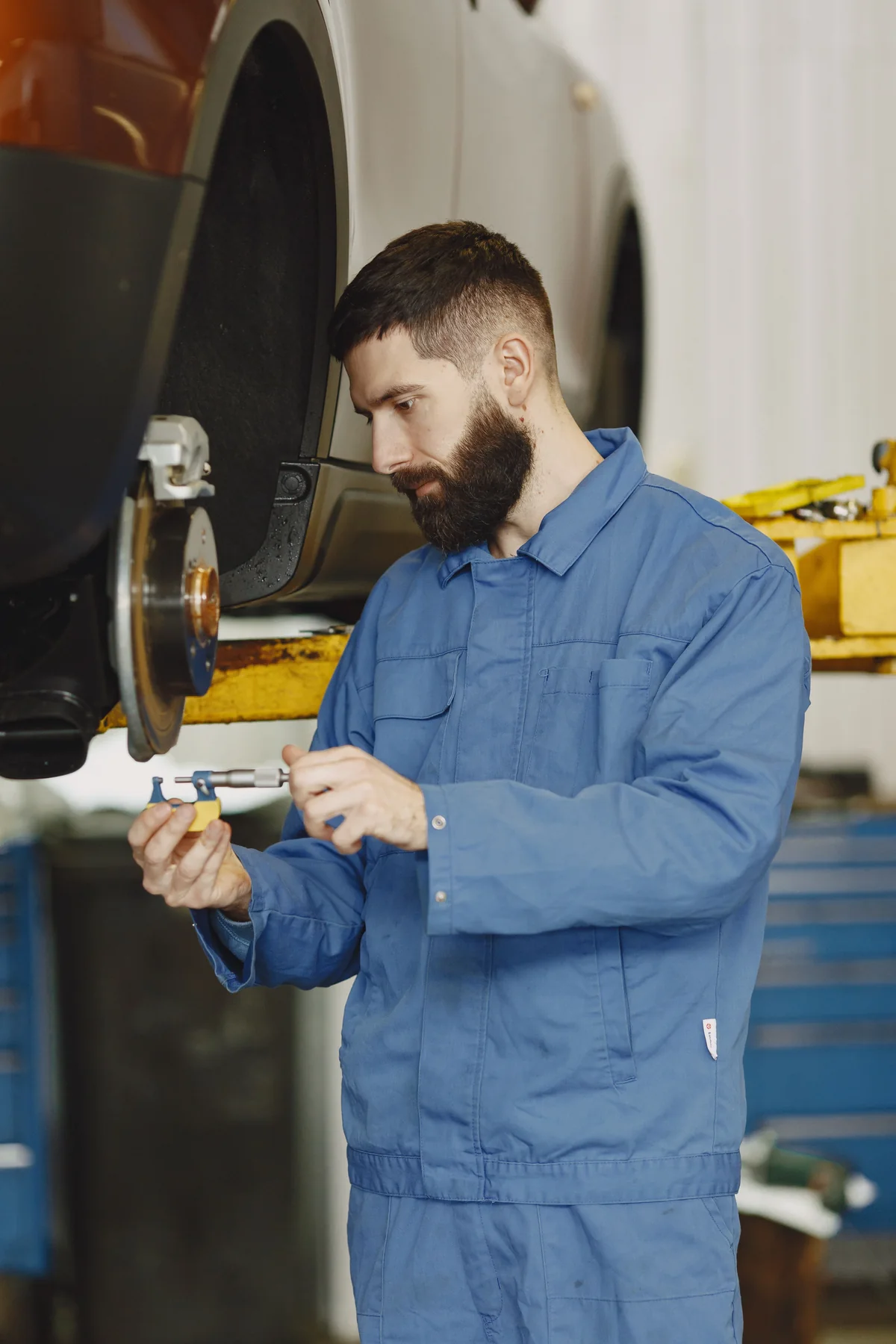 Fachkraft kontrolliert die Bremsanlage eines Autos
